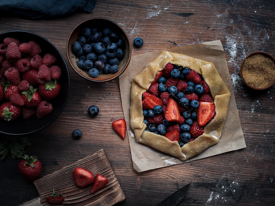 Berry Galette - scene with, strawberries and blackberries. Sugar sprinkled in a wooden table